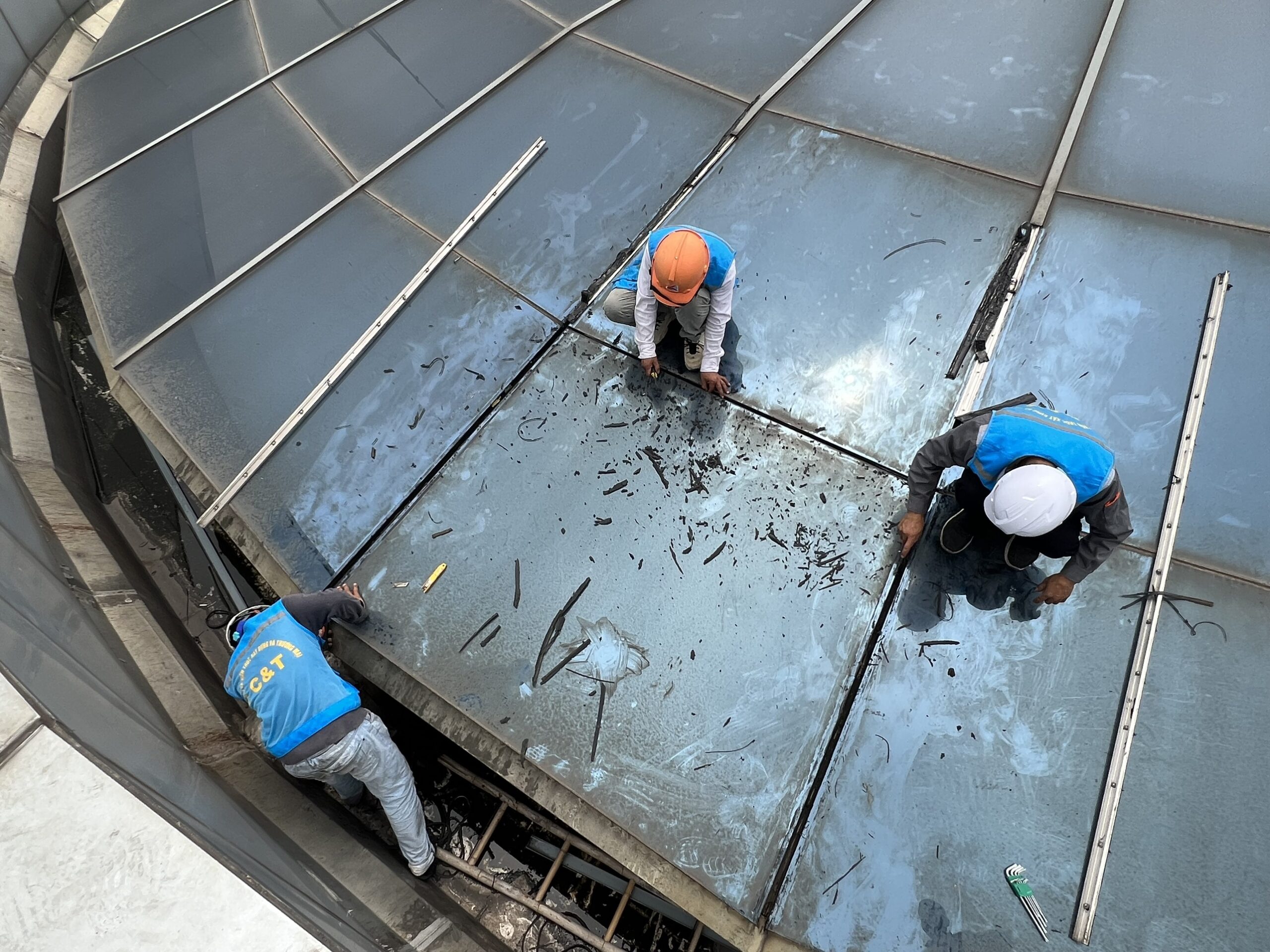 NHỰA KÍNH CƯỜNG LỰC ASIA LITE - GIẢI PHÁP THAY THẾ HOÀN HẢO CHO KÍNH HỘP CƯỜNG LỰC NHÂP KHẨU Công nhân C&T đang tiến hành tháo dỡ phần kính hộp cường lực bị hỏng